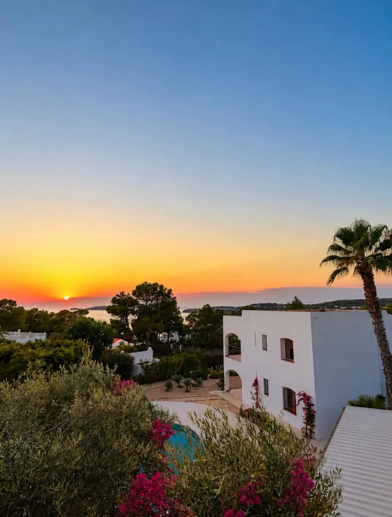 Atardecer sobre el mar desde la villa, con palmeras y la fachada encalada